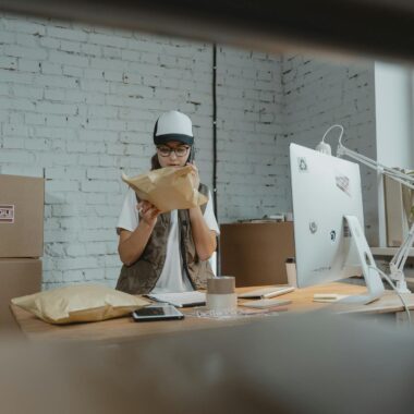 Courier in modern office checking parcel with technology and shipping materials around.
